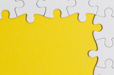 Sarı arka planda beyaz yapboz parçaları. İş solu