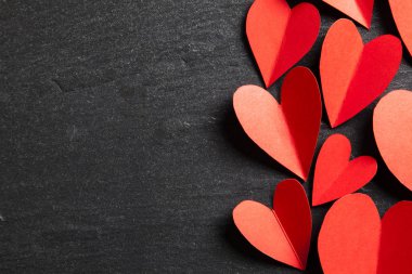 Arka planda kırmızı el yapımı kağıt kalpler.