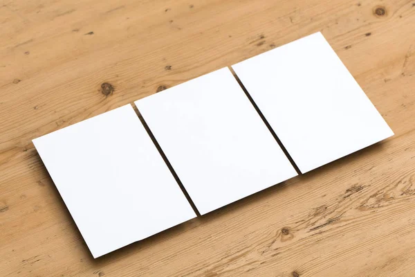 Folleto de tarjeta postal blanca en blanco sobre un fondo de madera — Foto de Stock