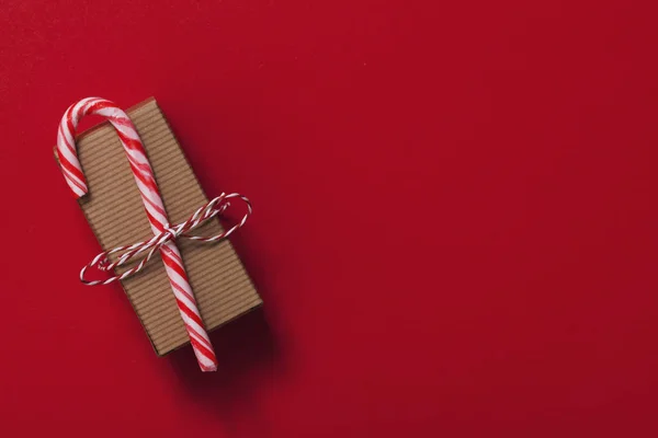 Feestelijk kerstcadeau met suikerriet op een rode achtergrond — Stockfoto