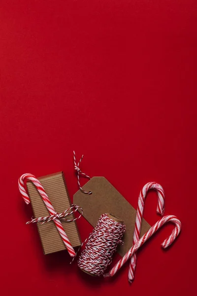 Presente de Natal festivo com cana-de-açúcar em um fundo vermelho — Fotografia de Stock