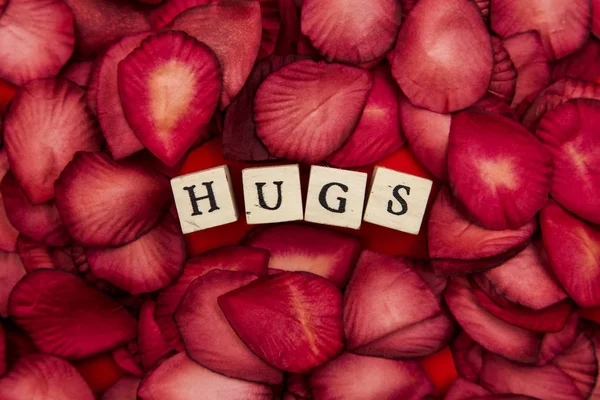 Red rose petals background with romantic hugs message — Stock Photo, Image