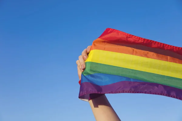 Concetto di orgoglio gay. mano tenendo un gay orgoglio LGBT arcobaleno bandiera . — Foto Stock