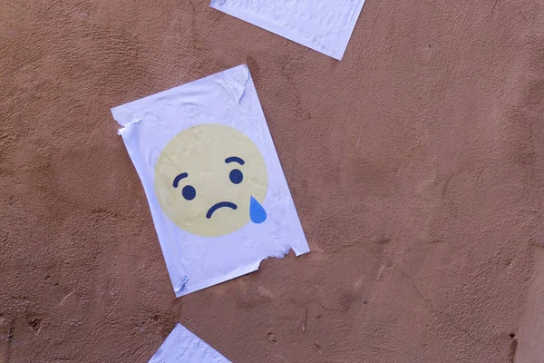 Personaje emoji llorón impreso en papel y pegado en una pared —  Fotos de Stock