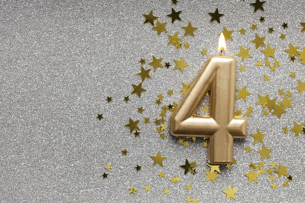 Number 4 gold celebration candle on star and glitter background — Stock Photo, Image