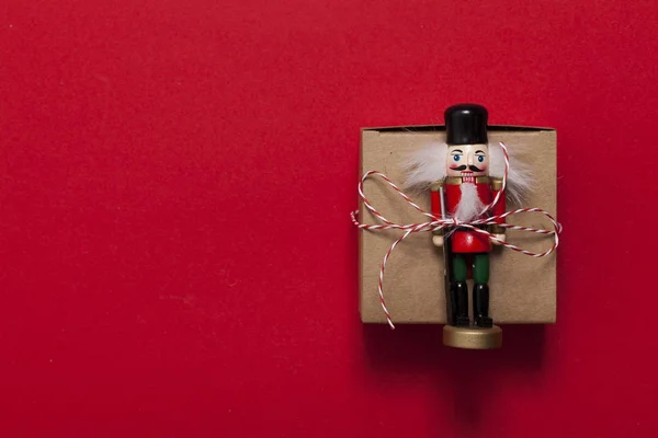 Kerstcadeau met notenkraker op een rode achtergrond — Stockfoto