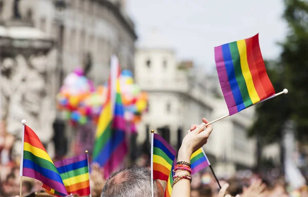 Um espectador acena uma bandeira do arco-íris gay em uma marcha do orgulho gay LGBT — Fotografia de Stock