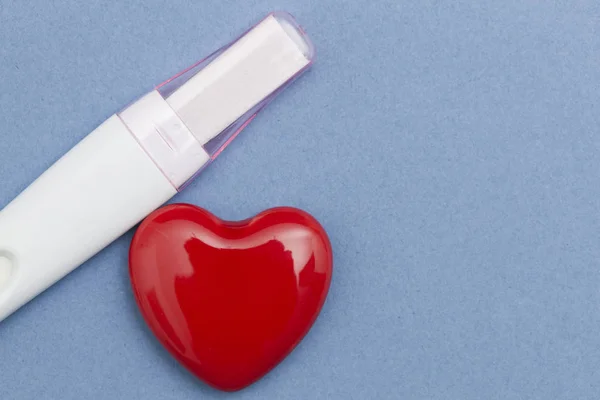 Pregnancy test with a red heart on a blue background — Stock Photo, Image