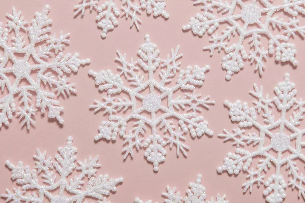 Bílé třpytky sněhové vločky složení na pastelově růžové pozadí — Stock fotografie