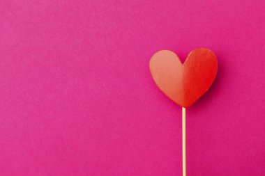 Kağıt kalp, parlak pembe arka planda bir çubuğun üzerinde