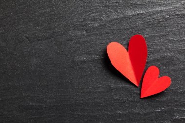 Arka planda kırmızı el yapımı kağıt kalpler.