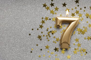 Yıldız ve ışıltılı arka plan üzerinde 7 numara altın kutlama mum