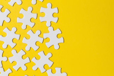 Sarı arka planda beyaz yapboz parçaları. İş solu