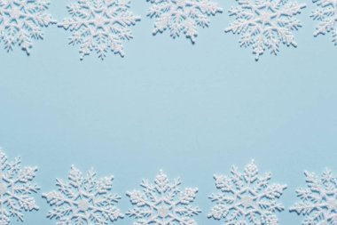 Pastel mavi zemin üzerine beyaz glitter kar tanesi kompozisyon