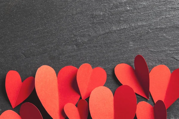 Rode handgemaakte papieren hartjes op een leistenen achtergrond — Stockfoto