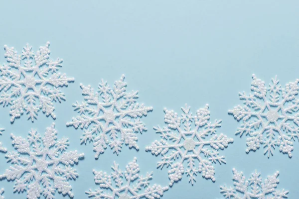 Pastel mavi zemin üzerine beyaz glitter kar tanesi kompozisyon — Stok fotoğraf