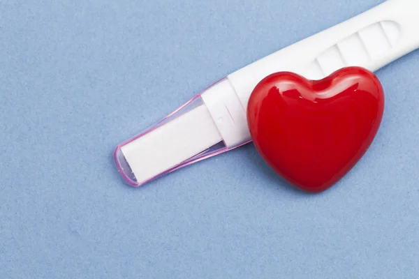 Zwangerschapstest met een rood hart op een blauwe achtergrond — Stockfoto