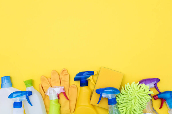 Spring cleaning spray bottle products on a bright yellow backgro