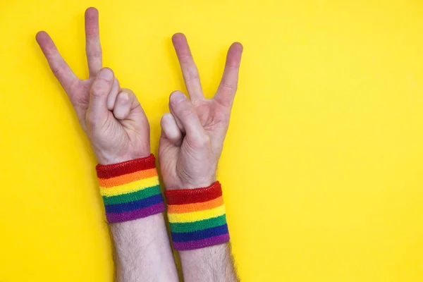 Victory hand gesture with gay pride rainbow flag wristband on a