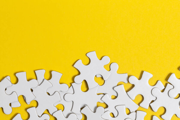 White jigsaw puzzle pieces on a yellow background. Business solu