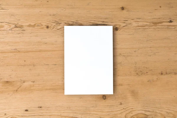 Folleto de tarjeta postal blanca en blanco sobre un fondo de madera — Foto de Stock