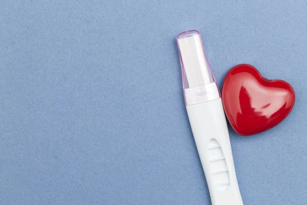 Zwangerschapstest met een rood hart op een blauwe achtergrond — Stockfoto