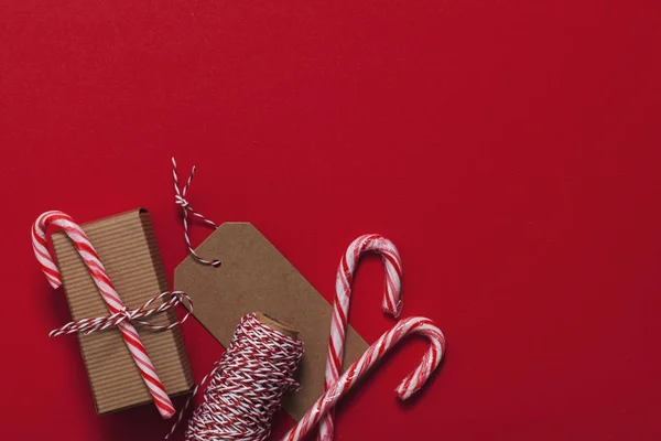 Presente de Natal festivo com cana-de-açúcar em um fundo vermelho — Fotografia de Stock