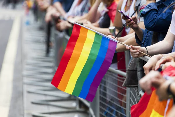 Um espectador acena uma bandeira do arco-íris gay em uma marcha do orgulho gay LGBT — Fotografia de Stock