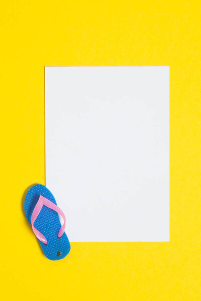 Summer flip flop sandals with a blank white sign on a bright yel