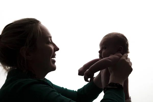 Silueta de una madre sosteniendo a su bebé recién nacido —  Fotos de Stock