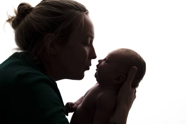 Silueta de una madre sosteniendo a su bebé recién nacido —  Fotos de Stock