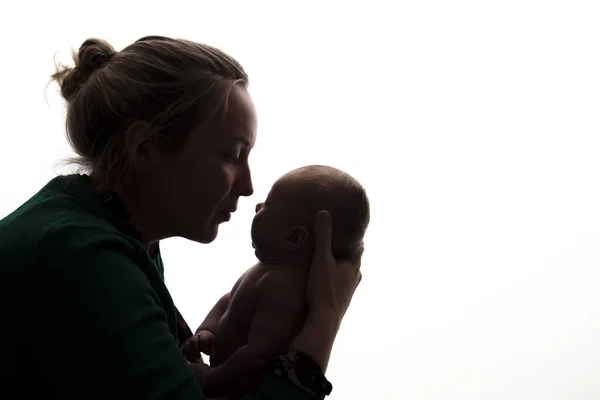 Silueta de una madre sosteniendo a su bebé recién nacido —  Fotos de Stock