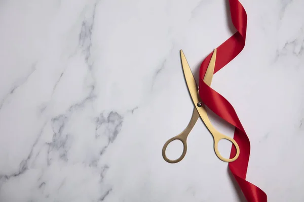 Grand opening background. Gold scissors with red ribbon on a marble background — Stock Photo, Image