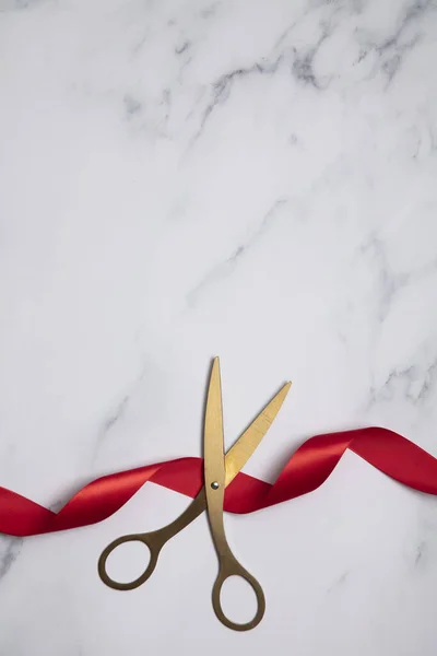 Грандиозное открытие. Золотые ножницы с красной лентой на мраморном фоне — стоковое фото