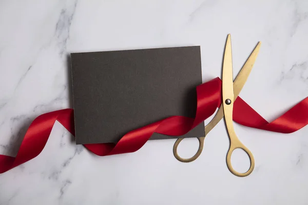 Grand opening background. Gold scissors with red ribbon on a marble background — Stock Photo, Image