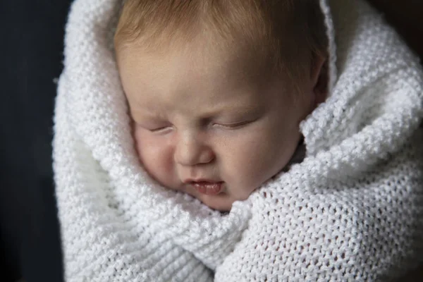 Um bebê de um mês de idade dormindo envolto em um cobertor branco — Fotografia de Stock