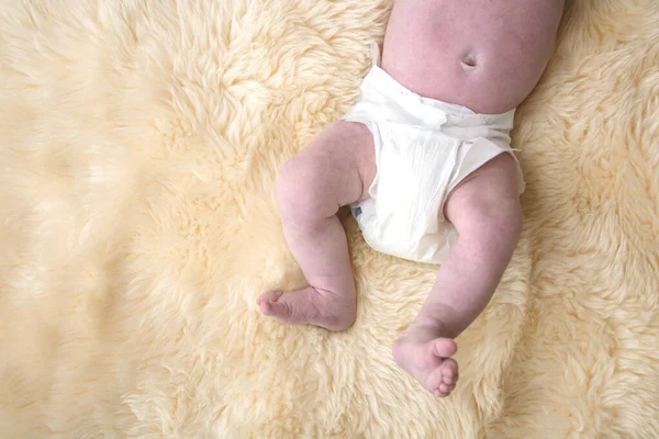 Newborn baby legs with white nappy, diaper on a fur background. — Stock Photo, Image