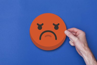 Bir emoji simgesini tutan erkek el mutsuz bir gülen kafa ikonu