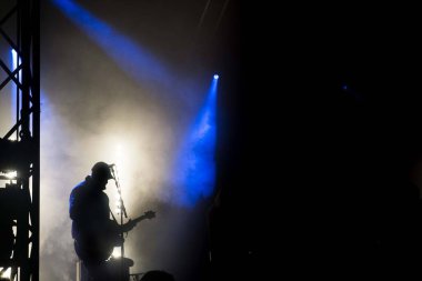 Konserde sahnede bir gitaristin silueti.