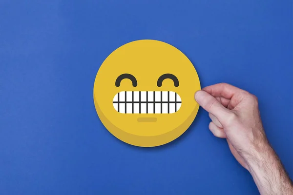 Mano maschile in possesso di un emoticon emoticon smiley icona della testa — Foto Stock