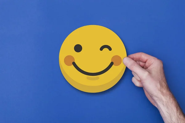 Männliche Hand mit einem Emoji-Emoticon Smiley-Kopf-Symbol — Stockfoto