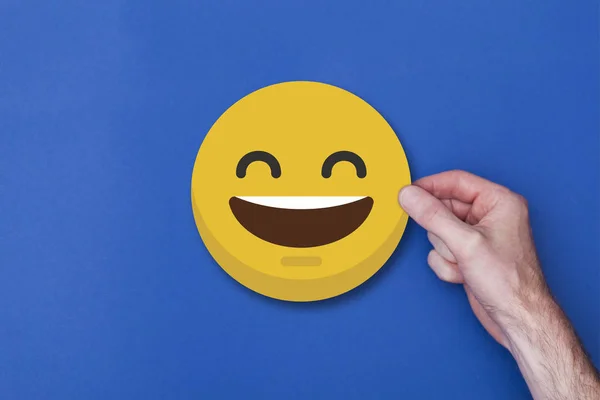 Man hand met een emoji emoticon smiley hoofd icoon — Stockfoto