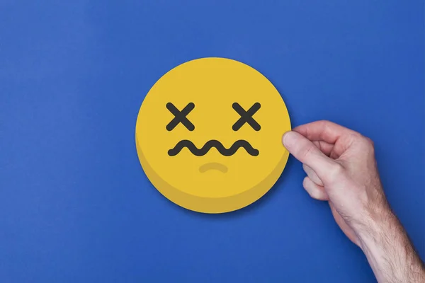 Bir emoji simgesini tutan erkek el mutsuz bir gülen kafa ikonu — Stok fotoğraf