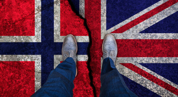Деловой человек стоит на потрескавшемся флаге Великобритании и Норвегии. Политическое понятие
