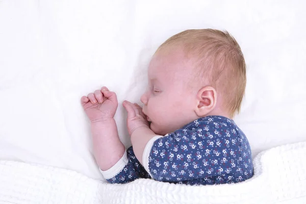 Bebê recém nascido dormindo em um lençol branco. Bonito bebê jovem — Fotografia de Stock