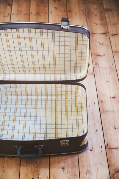 Ein offener alter alter brauner Reisekoffer auf einem Holzboden — Stockfoto