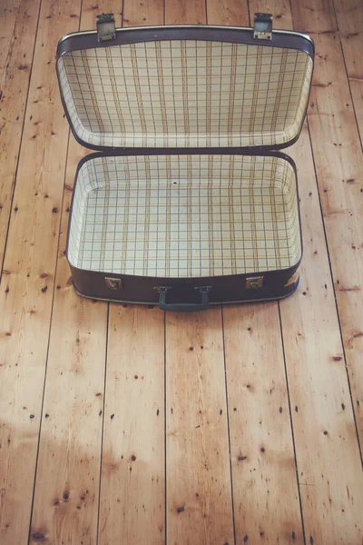 Ein offener alter alter brauner Reisekoffer auf einem Holzboden — Stockfoto