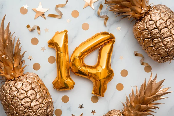 14-te urodziny kartka ze złotymi balonami foliowymi i złotymi ananasami — Zdjęcie stockowe