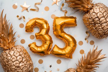 Altın folyo balonlar ve altın ananaslarla dolu 35. Doğum günü kartı