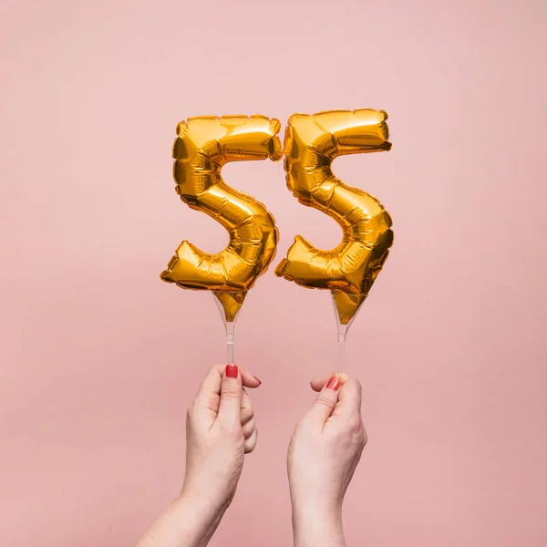 Kvinnlig hand håller en nummer 55 födelsedag firande guld ballong — Stockfoto